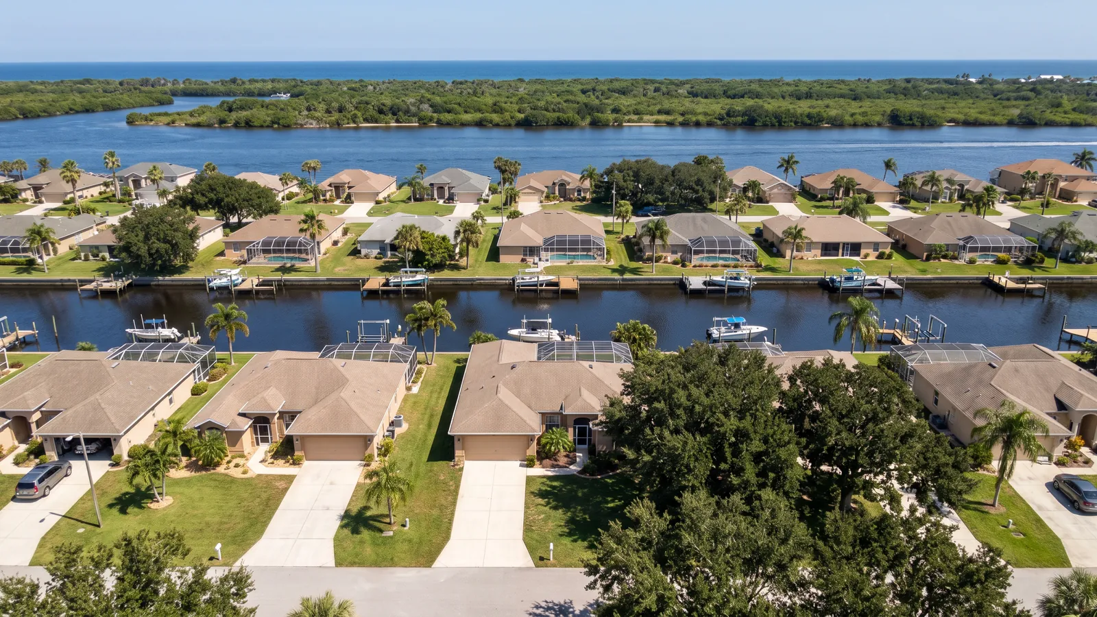 Aerial view of saltwater canal homes and driveways in Palm Harbor, Palm Coast, with the Intracoastal and barrier island beyond